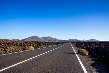Spain, Lanzarote, Perfect asphalt street through rough lava field of timanfaya area