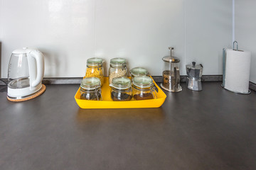 glass stylish vintage jars with different food and teapot in Interior of the modern kitchen in loft flat apartment in minimalistic style with yellow color. Oatmeal, cornflakes, coffee tea