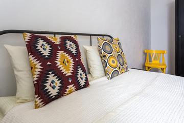 colorful pillows on the bed in Interior of the modern bedroom in loft flat apartments in light color style