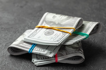 Stacks of cash dollars tied with colored office bands on dark background. Concept of savings or bribe