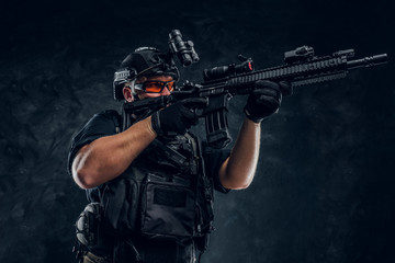 Special forces soldier holding an assault rifle with a laser sight and aims at the target.