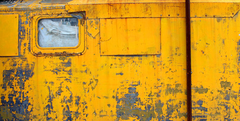metal wall with yellow peeling paint with window