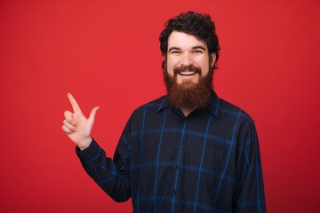 Bearded guy with toothy smiling looking at camera while pointing up