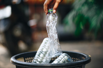 hand throwing empty plastic water bottle in recycling bin