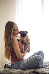 blonde girl with kisses and holds pug puppy