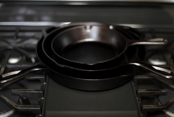 Cast iron skillets on a modern gas stove oven in a home.