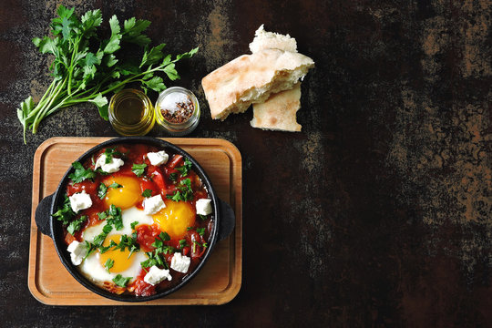 Shakshuka. Middle Eastern cuisine. Arabic, Israeli, Moroccan breakfast or lunch. Fried eggs in tomato and vegetable sauce with spices and herbs.