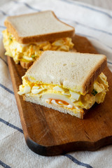 Homemade egg salad sandwich on wooden board, low angle view. Closeup.