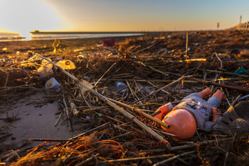 Ein Puppe und viel Kunststoffmüll und Verpackungsmüll am Strand