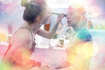 make-up salon on a blurred background with a pink bokeh / client makeup salon, a young girl with beautiful skin and a face doing make-up in the salon