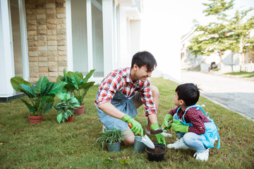 dad and son planting a plant gardening at their house together. parenting outdoor activity with son