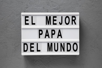 Top view, 'El Mejor Papa Del Mundo' words on modern board over concrete surface. Overhead, from above, flat lay. Father's day.