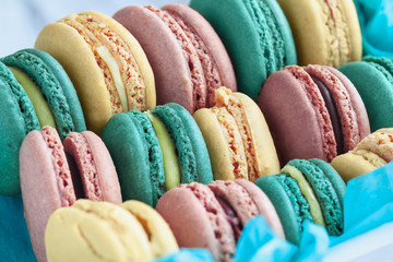Assortment of fresh french macarons packaged in a pretty blue paper with blurred  background..