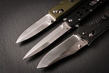 Folding knives on a dark background.