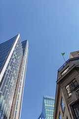 Naklejka premium Old and new building facades together at a bright sunny day on the blue sky background. Economy finances and business activity concept. Low angle view