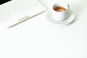 Coffee cup, laptop and on white table. Selective focus.