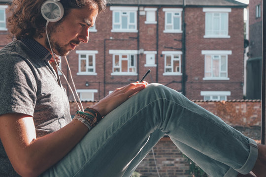 Caucasian listening music with white headphones