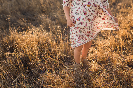 Young girl swinging dress in California field during sunset