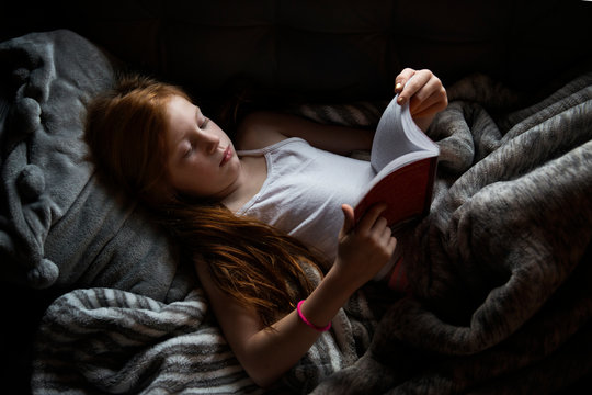 Little Girl Lying Down Reading a Book