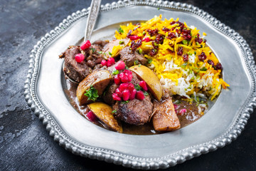 Traditional Iranian khoresh beh stew with chunks of lamb, quinces and saffron rice as a closeup on a pewter plate