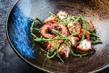 Traditional French octopus braised cooked with Salicornia, lemon curd and spice as closeup in a modern design Japanese bowl