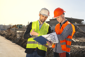 two men are builders workers are engineers at a construction site are looking at the drawings in...
