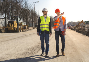 two men are builders workers are engineers at a construction site are looking at the drawings in helmets