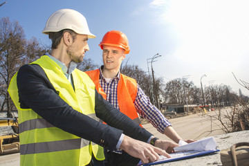 two men are builders workers are engineers at a construction site are looking at the drawings in...