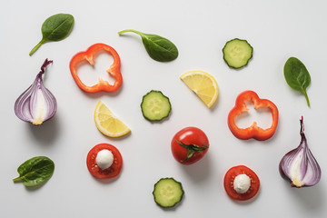 top view vegetable slices - tomatoes, cucumber, pepper, greens , lemon on white background.