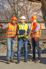 male workers engineers in helmets talking near the bulldozer and excavator