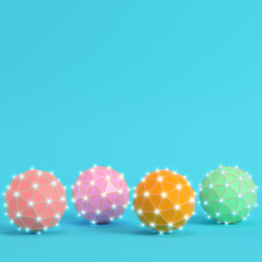 Four colorful low poly abstract glowing spheres on bright blue background in pastel colors