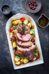 Barbecue marinated Greek lamb roast with tomatoes, potatoes and olives as top view in a roasting dish © HLPhoto