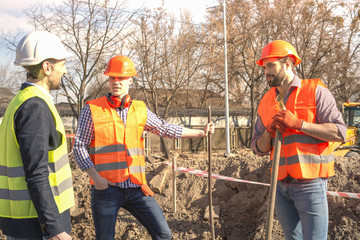 male workers engineers in helmets with the head, work, in the hands of a shovel