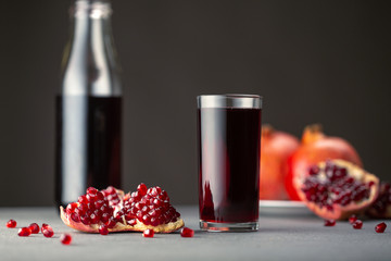 Pomegranate juice in a glass on gray background.