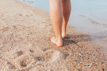 Woman walking on the beach leaving footprints in the sand 