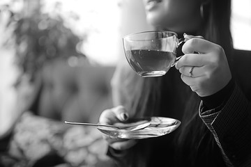 girl in a cafe drinking tea / a modern cafe, a young adult model drinking tea and holding a cup in her hand
