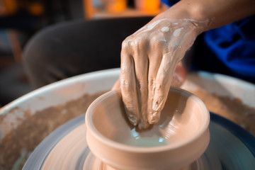 Working process of man's work at potters wheel in art studio. Unknown craftsman creates jug. Focus...