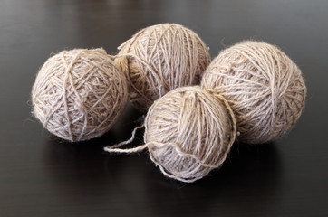 Home hobby.Four balls of gray thread and one color lie on a dark wooden table.