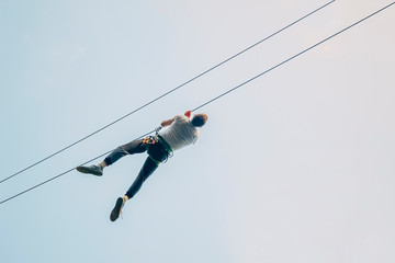 Fototapeta na wymiar Man descend on a zip line. Adult man zip line adventure. Zipline is an exciting adventure activity. 