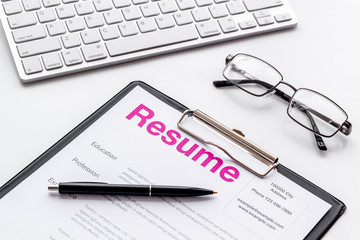 Create CV concept with pen, glasses, keyboard on white desk top view