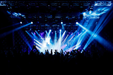 A lot of hands, crowd on concert, blue light.