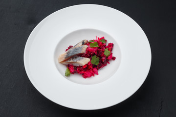 Beet with herring and parsley on a white plate