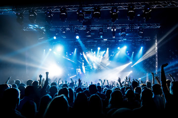 A lot of hands, crowd on concert, blue light.