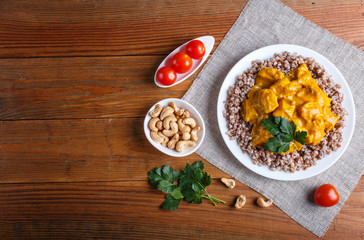 Buckwheat with chicken curry sauce with cashew on brown wooden background.