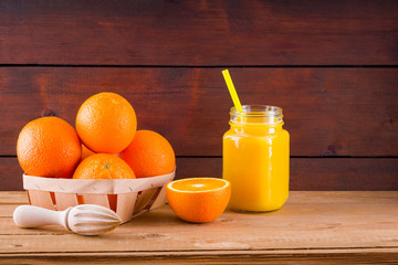 Orange fruits and juice on wooden boards. Citrus fruit for making juice with manual juicer. Oranges in wooden box. Mason jar with orange juice