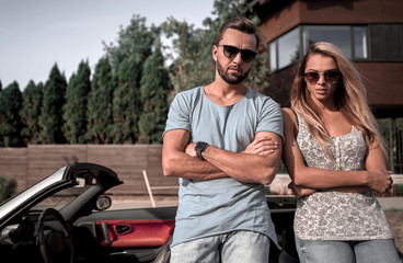 Naklejka premium young couple standing near luxury car.