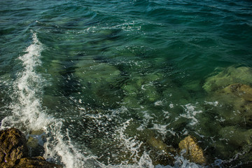 waterfront transparent green water surface natural background local scenic landscape from above with waves breaking on stone