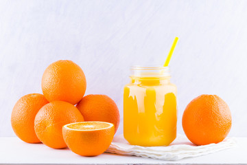 Orange fruits and juice on white background. Citrus fruit for making juice with manual juicer. Oranges on white napkin. Mason jar with orange juice