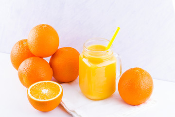 Orange fruits and juice on white background. Citrus fruit for making juice with manual juicer. Oranges on white napkin. Mason jar with orange juice