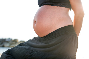 Pregnant woman, belly seen against the sun
